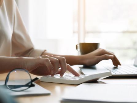 Frau arbeitet an Laptop mit Rechner