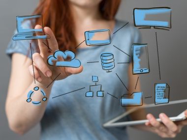 Frau zeigt auf vernetzte gezeichnete IT Anlage wie Laptop Server und Cloud